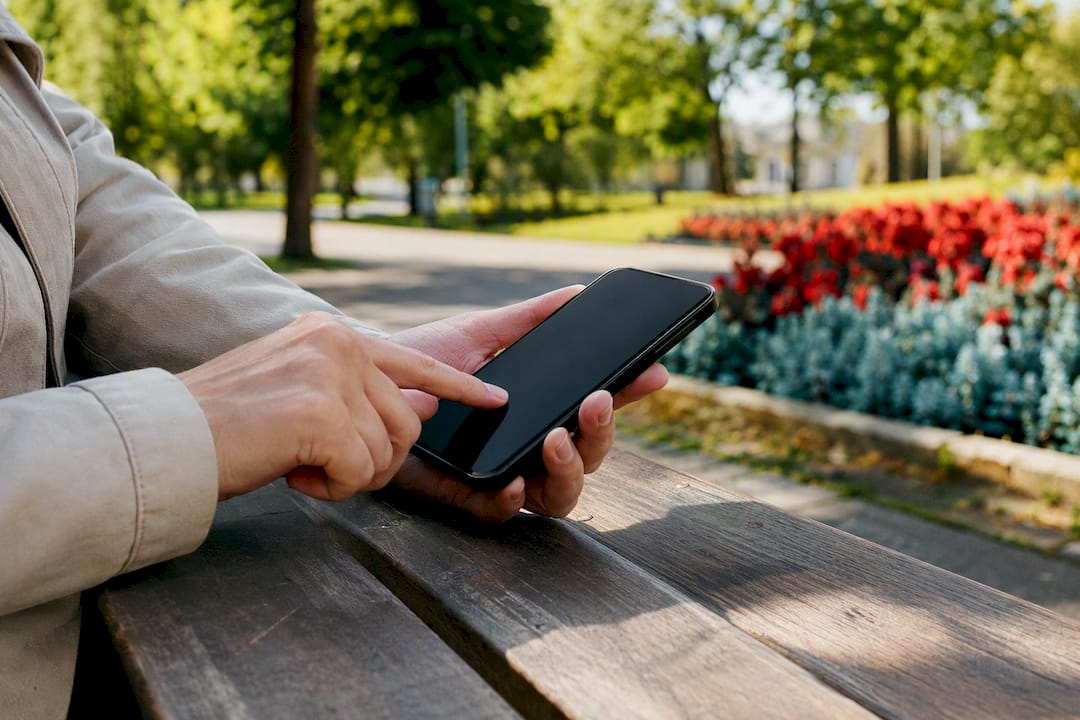 Hands tapping a smartphone screen outdoors