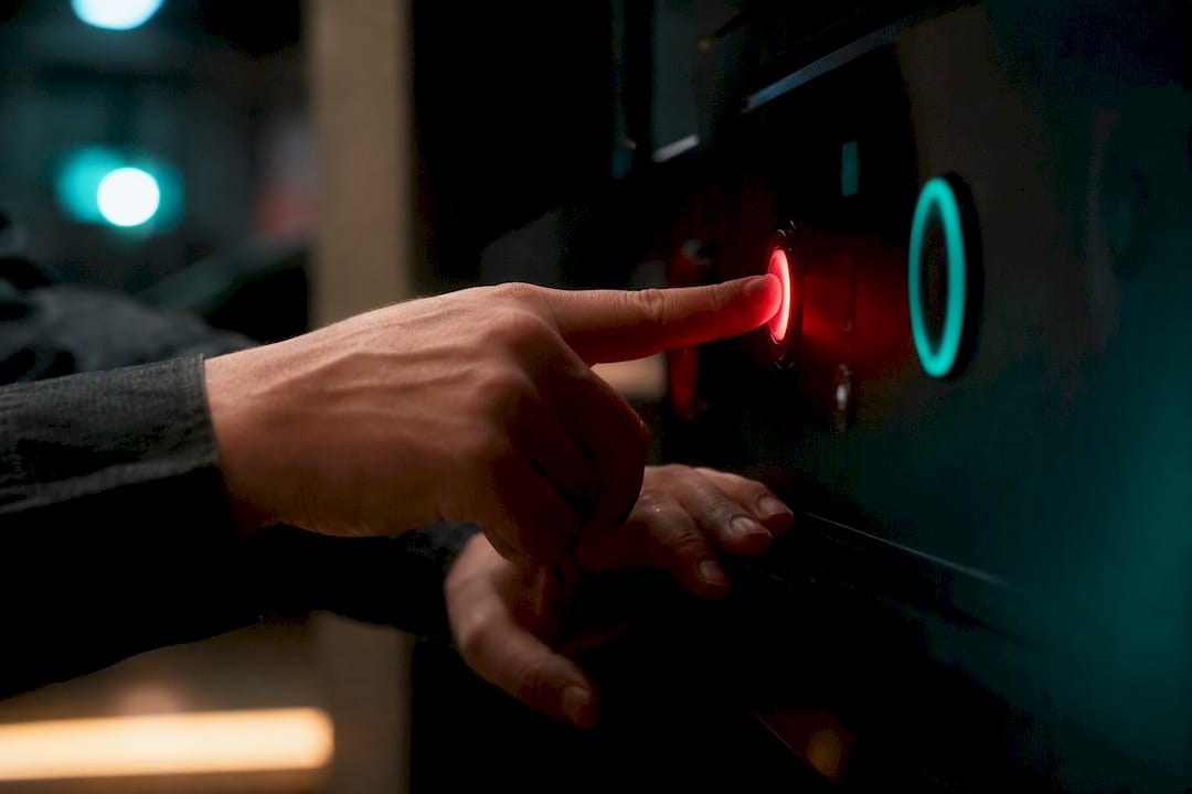 Hands pressing alarm button in dark office